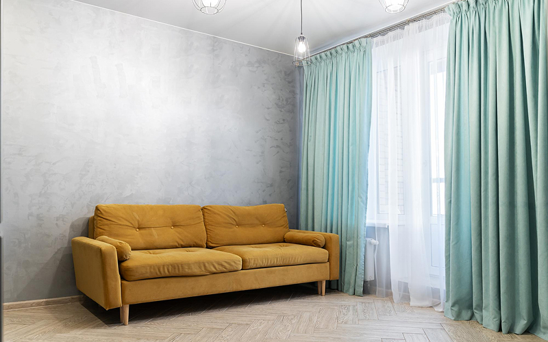 Mustard yellow sofa paired with teal floor-to-length HDB curtains.