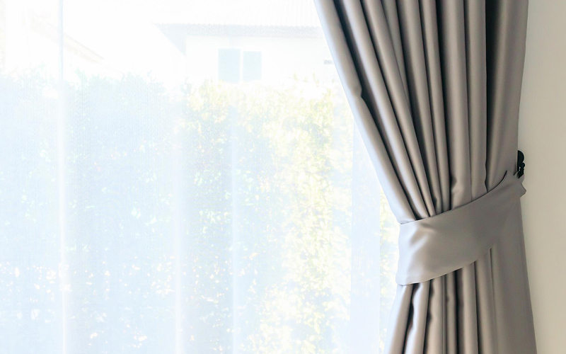 Grey curtains tied back to block HDB noise.