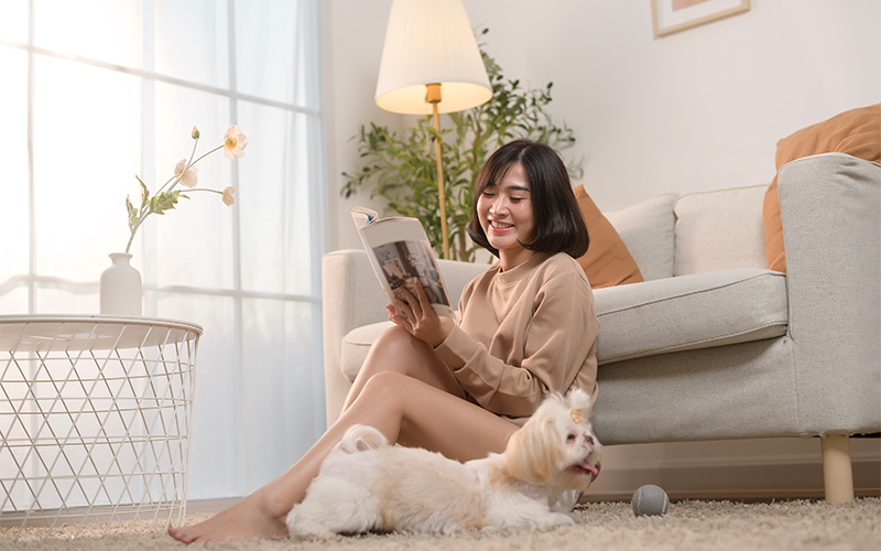 Woman reading with dog in pet-friendly living room design.